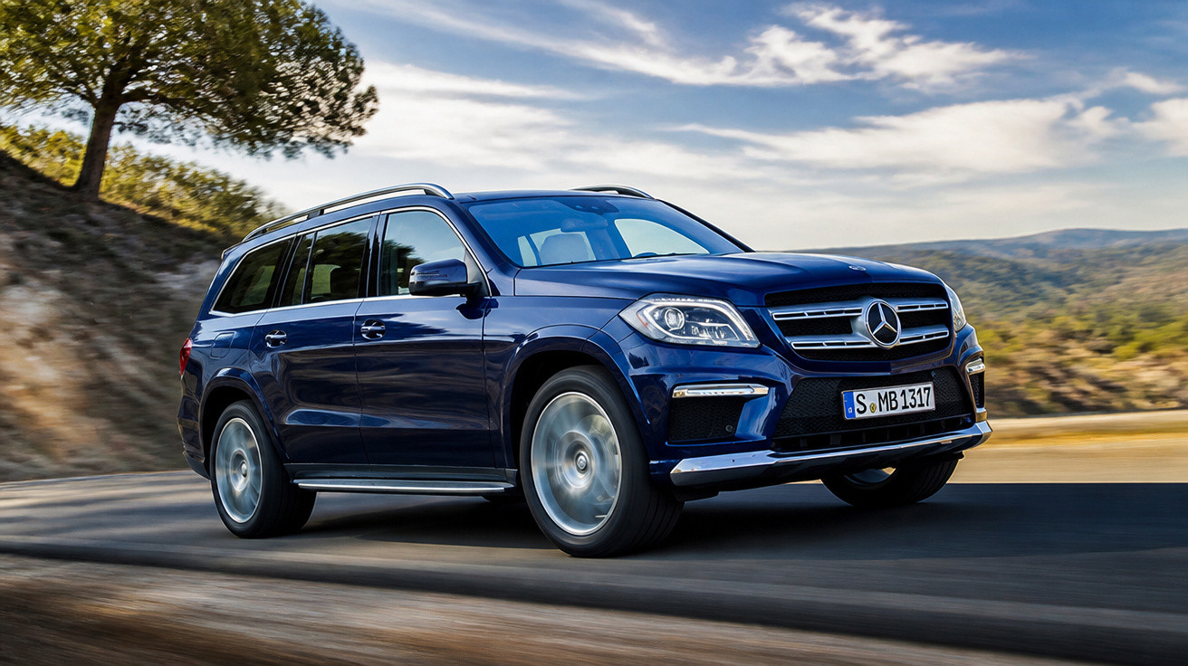 Blauer Mercedes-Benz SUV fährt auf kurviger Landstraße mit Bäumen und Bergen im Hintergrund.