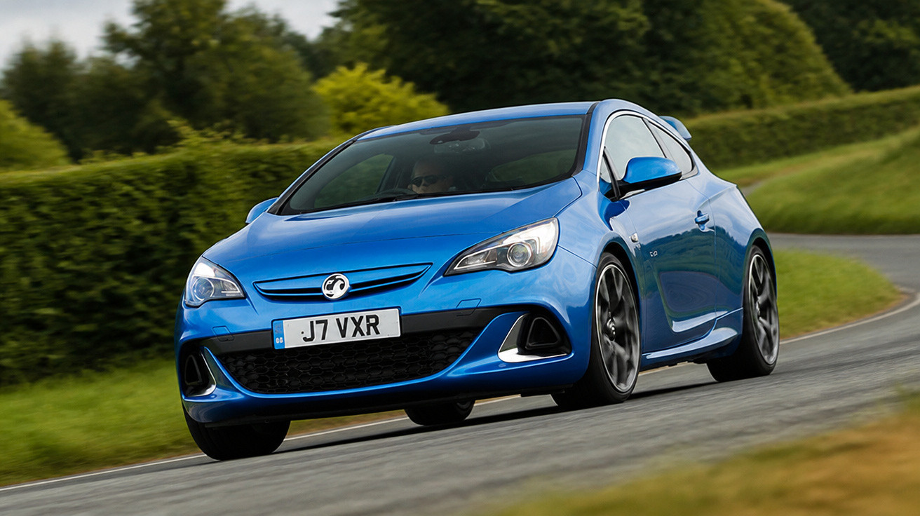 Blauer Vauxhall Astra GTC fährt auf kurviger Landstraße mit grünem Hintergrund