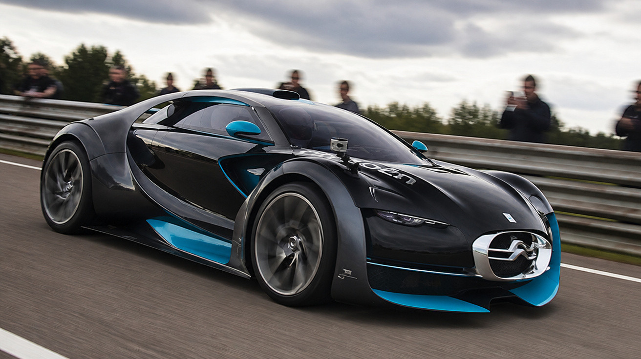 Schwarzer futuristischer Sportwagen mit blauen Akzenten fährt auf Rennstrecke, Zuschauer im Hintergrund.
