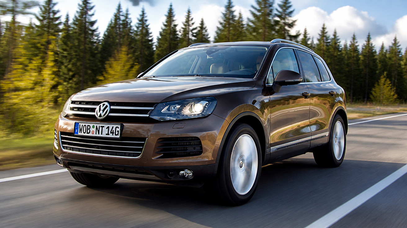 Brauner Volkswagen SUV fährt auf Landstraße mit Wald im Hintergrund bei Tageslicht.