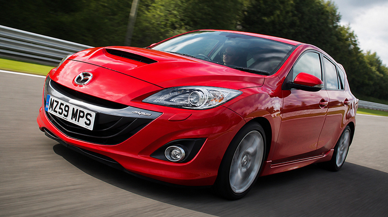 Roter Mazda 3 MPS Sportwagen fährt dynamisch auf einer Rennstrecke bei sonnigem Wetter.