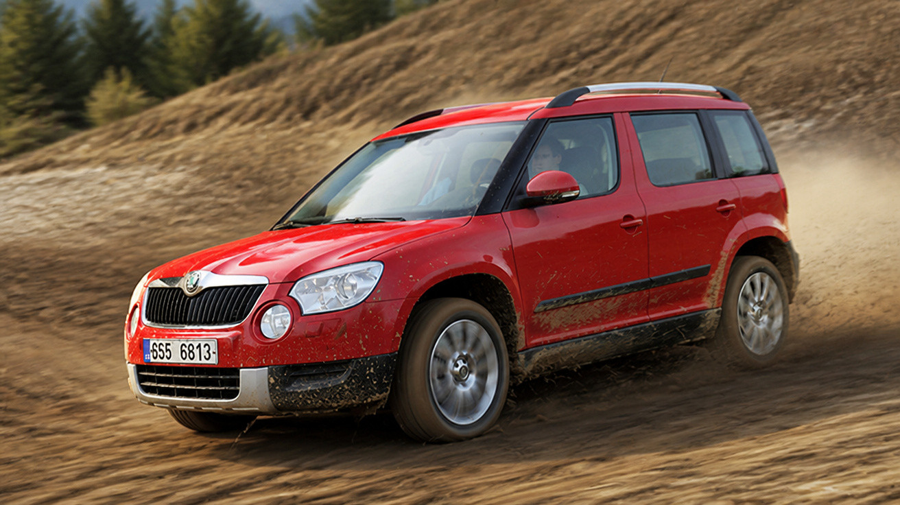 Roter Skoda SUV fährt schnell auf einem schlammigen Gelände mit Wald im Hintergrund.