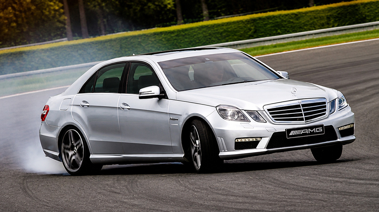 Silberner Mercedes-Benz AMG driftet auf Rennstrecke, Rauch steigt von Hinterreifen auf.